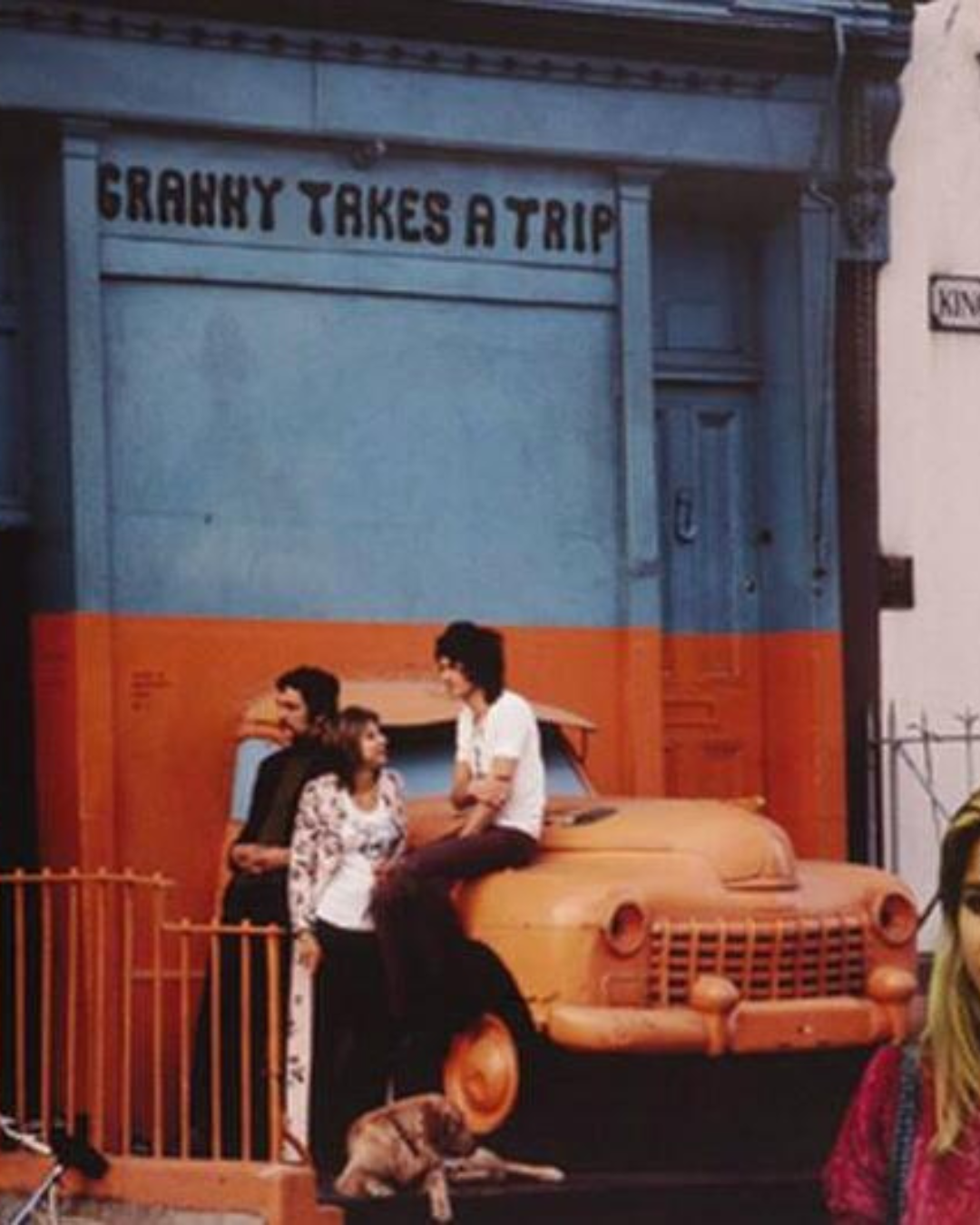 Granny Takes a Trip Shop window in 1969. bonnet of an orange vintage beetle coming through a wall with people sat on the Bonnet